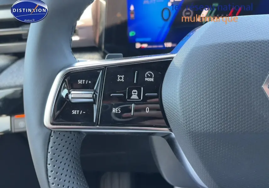 Gros plan sur les commandes gauche du volant gris d’une Renault Clio VI avec affichage numérique en arrière-plan.