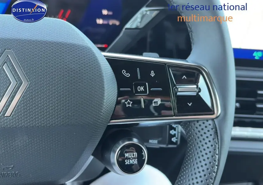 Gros plan sur le volant gris perforé de la Renault Clio VI avec commandes multifonctions et bouton Multi Sense.