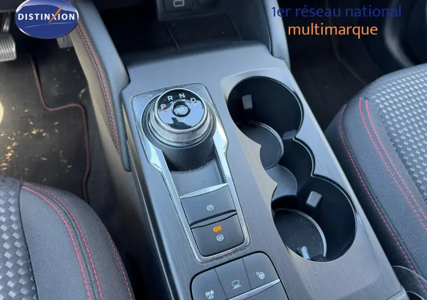 Vue rapprochée de la console centrale du Ford Kuga gris magnétique, mettant en valeur la molette de boîte automatique et les porte-gobelets.