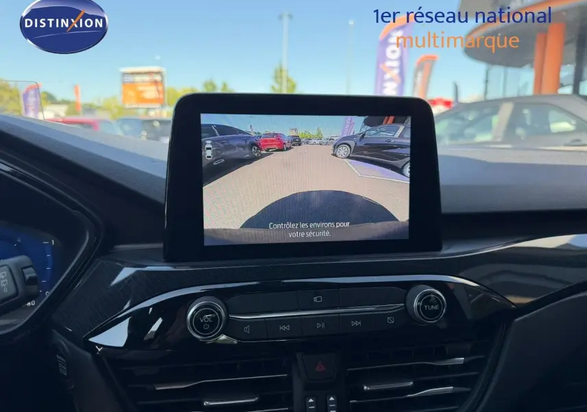 Vue intérieure du tableau de bord du Ford Kuga 2024 avec écran central affichant la caméra de recul, ambiance noire et finitions brillantes.