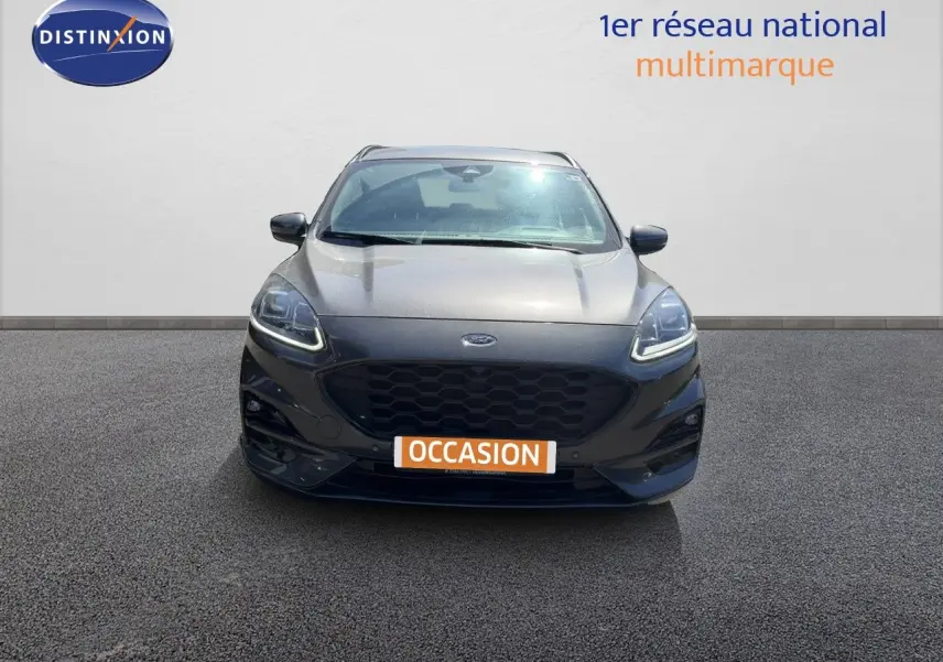 Vue frontale d’un Ford Kuga gris magnétique métal 2024 avec calandre noire et phares LED allumés.