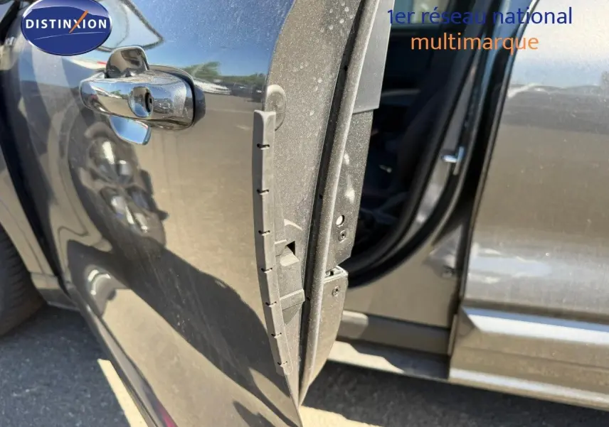 Vue rapprochée de la porte avant gauche ouverte d’un Ford Kuga 2024 gris magnétique métal, avec reflet et intérieur partiellement visible.