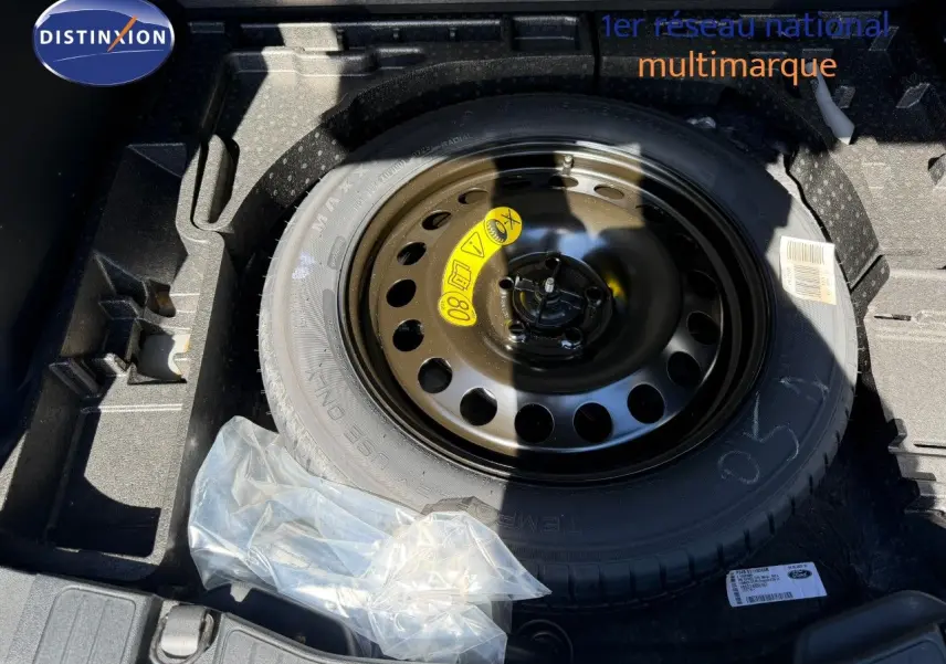 Vue rapprochée de la roue de secours noire dans le coffre du Ford Kuga 2024 gris magnétique métal.