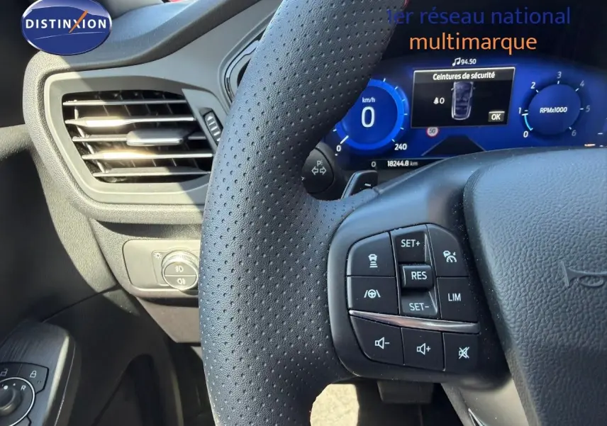 Gros plan sur le volant perforé et le tableau de bord numérique bleu du Ford Kuga 2024, version ST-LINE.