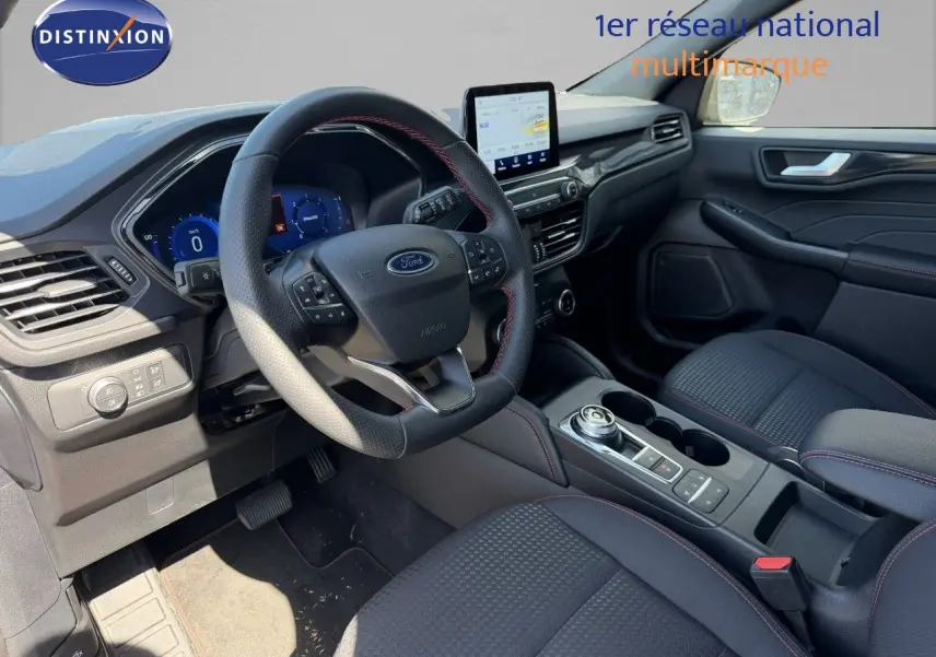 Intérieur avant du Ford Kuga 2024, volant cuir noir avec surpiqûres rouges et écran tactile central visible.