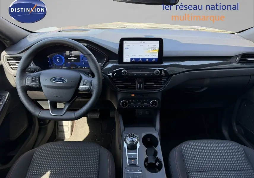 Vue intérieure frontale du Ford Kuga 2024 gris magnétique, avec tableau de bord numérique et écran tactile central.