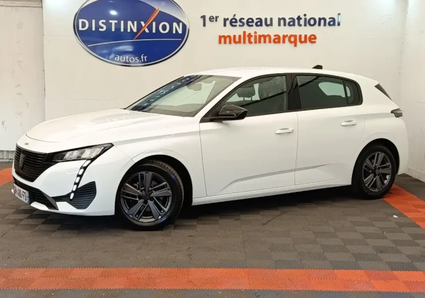 Peugeot 308 blanche vue de profil droit en intérieur, avec feux LED et jantes alliage foncé.