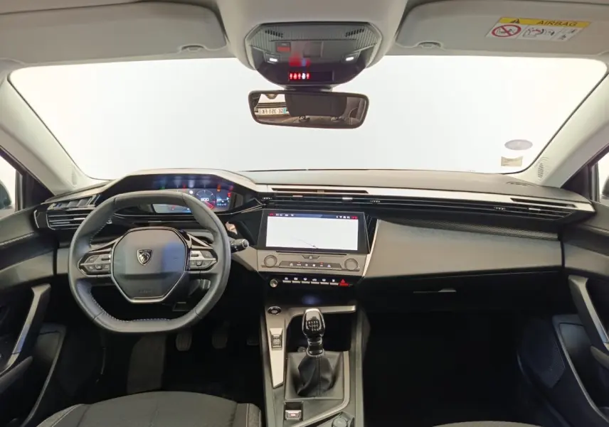Vue intérieure avant de la Peugeot 308 PureTech 130 blanche, tableau de bord moderne avec écran tactile et volant cuir multifonctions.