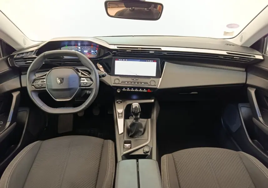 Vue intérieure avant de la Peugeot 308 2023, volant cuir, écran tactile central et levier de vitesses manuel noir.