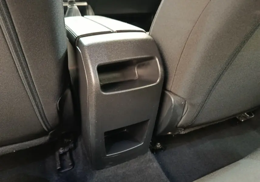 Détail de la console arrière noire entre les sièges arrière gris foncé d'une Peugeot 308 2023.