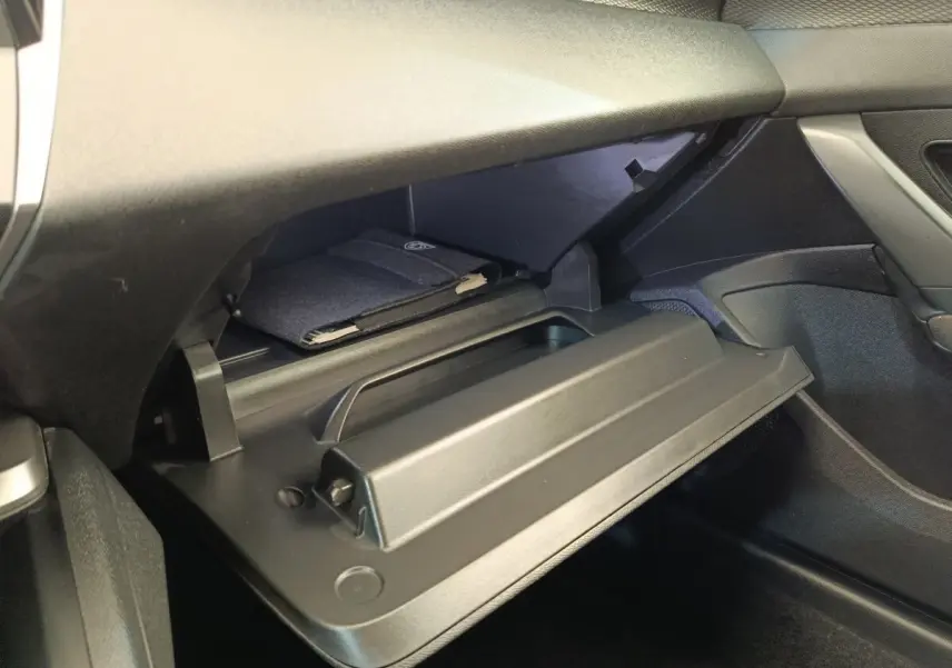 Intérieur de la Peugeot 308 2023, vue sur la boîte à gants ouverte côté passager avec un manuel à l'intérieur.