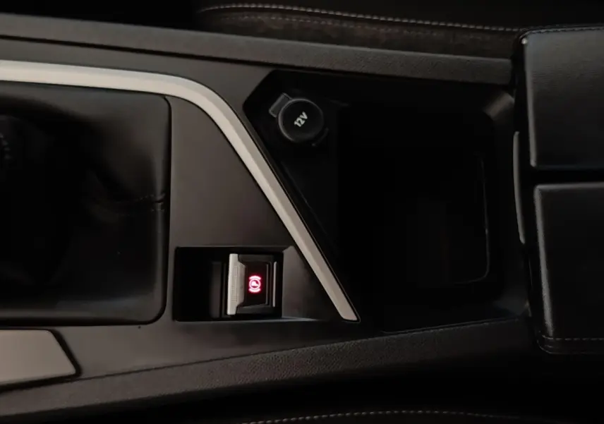 Gros plan sur la console centrale noire de la Peugeot 308 blanche, avec frein à main électrique activé.