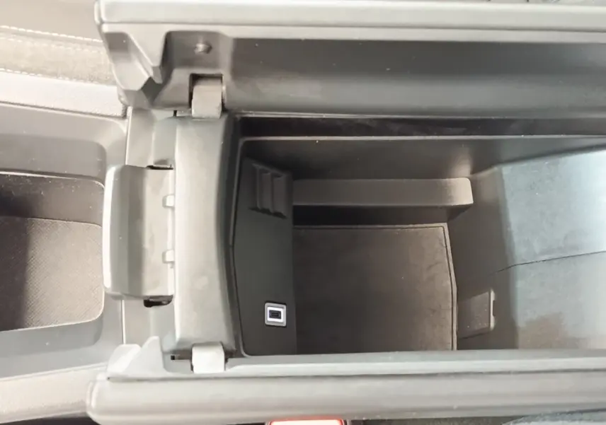 Vue intérieure en plongée du rangement central ouvert de la Peugeot 308 blanche, montrant un port USB intégré.