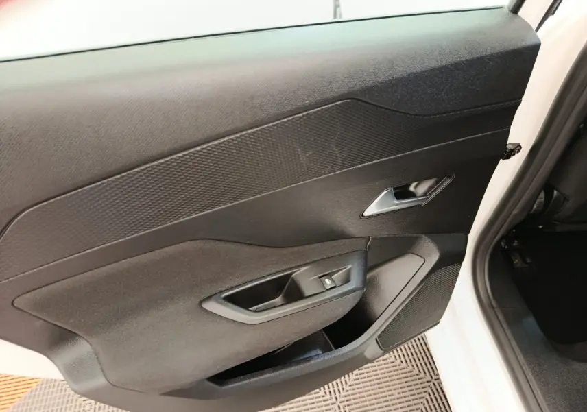 Vue intérieure côté gauche de la porte avant d'une Peugeot 308 blanche, avec panneau noir et commande de vitre.