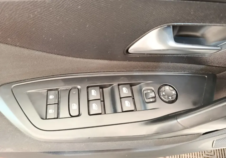 Gros plan sur les commandes de lève-vitres et rétroviseurs côté conducteur d'une Peugeot 308 blanche de 2023.