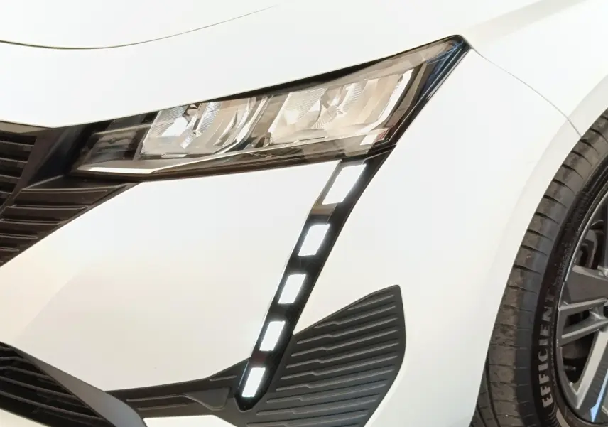 Gros plan sur le phare avant droit blanc de la Peugeot 308 2023 avec feux LED en forme de griffes verticales.