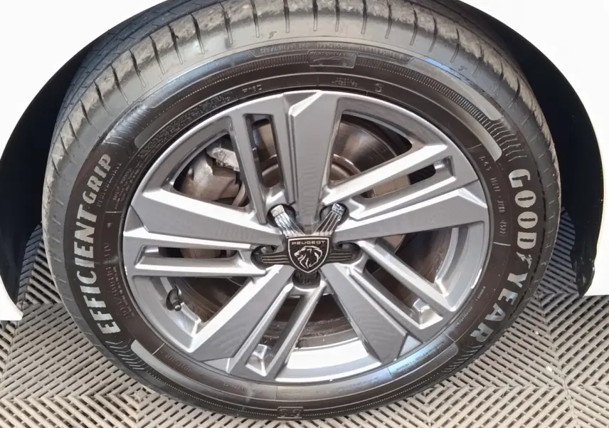 Gros plan sur la roue avant droite d’une Peugeot 308 blanche, avec jante alliage et pneu Goodyear EfficientGrip.