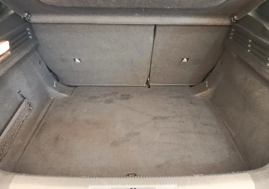 Coffre ouvert de la Peugeot 308 blanche, vue intérieure montrant l'espace de chargement avec banquette arrière rabattable.