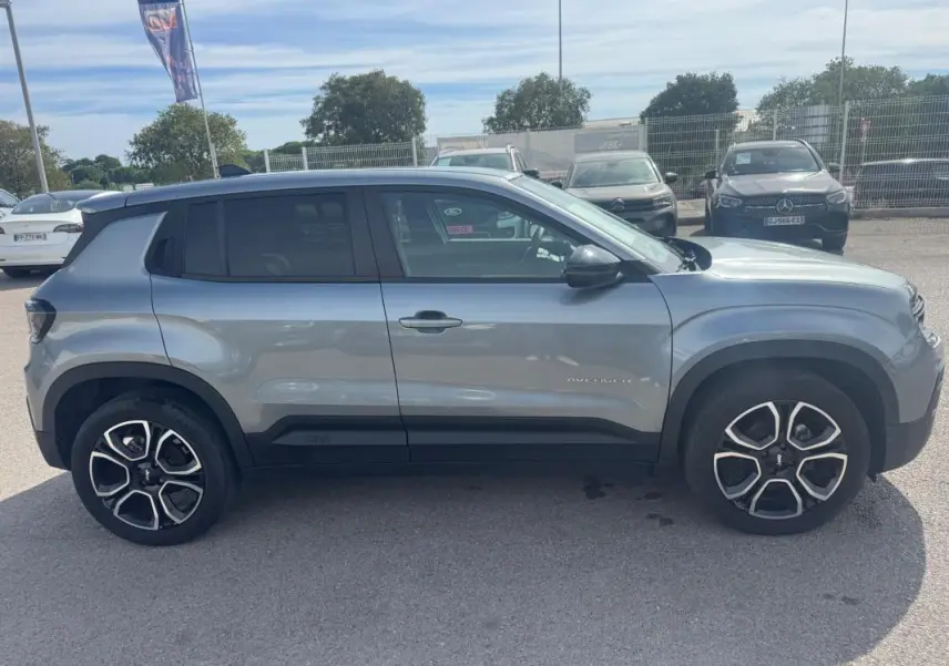 Vue de profil côté gauche du Jeep Avenger gris foncé 2025, avec jantes distinctives et toit noir contrastant.