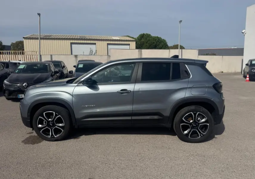 Vue de profil côté gauche d'un Jeep Avenger gris foncé 2025 avec jantes noires et toit contrasté.