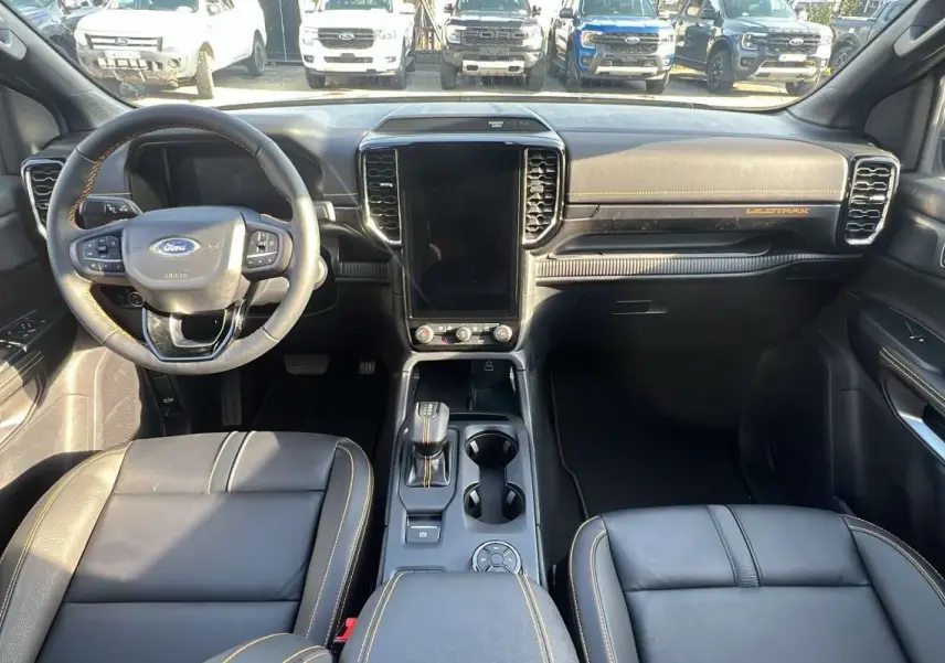 Vue intérieure avant du Ford Ranger Wildtrak 2026 gris iconic, avec volant cuir multifonctions et écran tactile vertical.