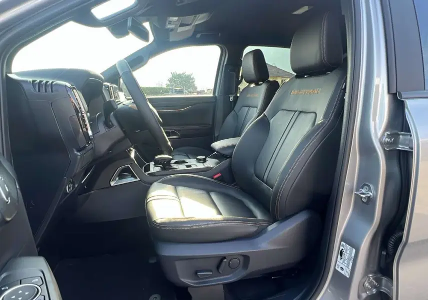 Vue intérieure côté conducteur du Ford Ranger gris iconic, sièges cuir noirs Wildtrak avec surpiqûres contrastées.