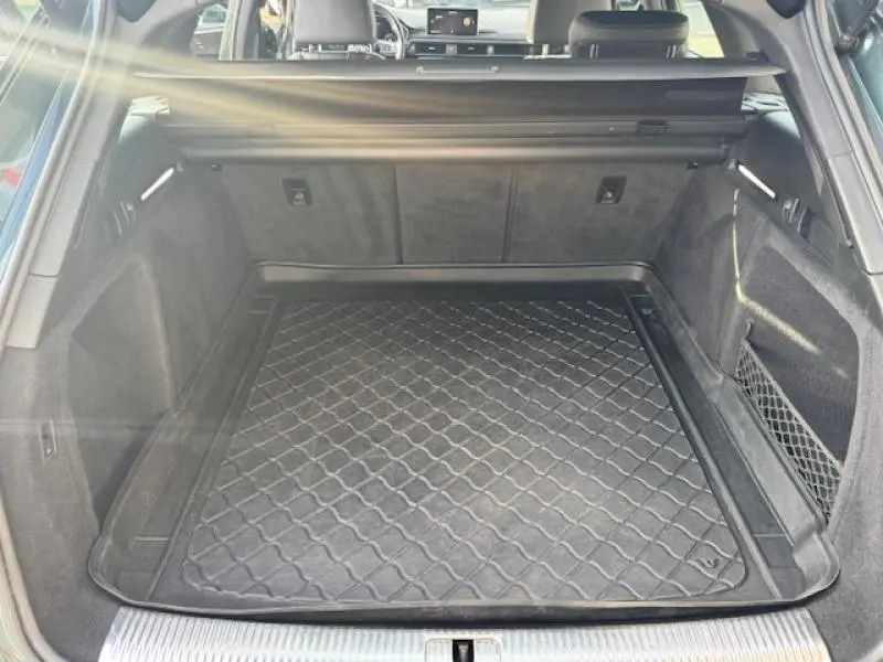 Coffre ouvert vu de l'arrière d'une Audi S4 Avant 2017 vert Gotland avec tapis de protection noir et filet latéral.