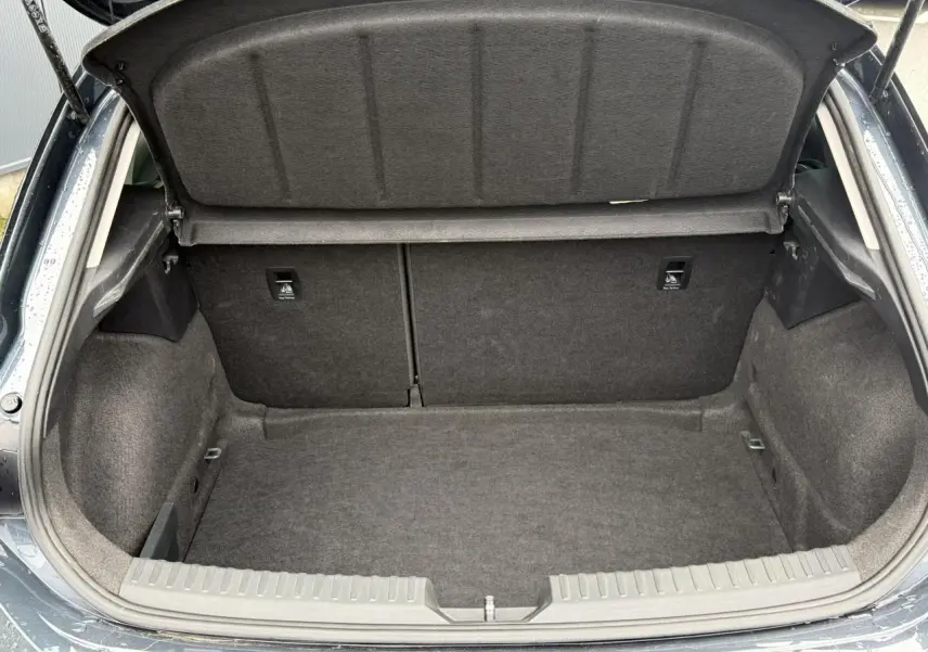 Coffre ouvert vu de l'arrière d'une SEAT LEON 1.5 TSI 115 Style gris magnétique, intérieur de coffre en tissu gris.
