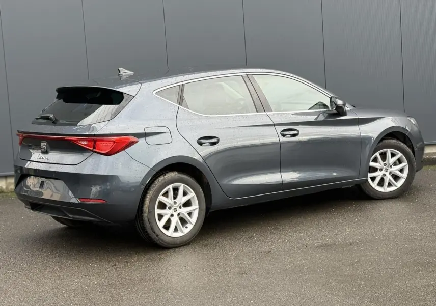 SEAT Leon 1.5 TSI 115 Style gris magnétique vue de profil côté droit sur sol humide devant un mur gris.