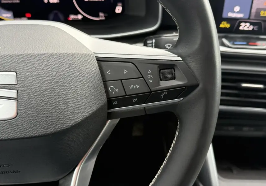 Gros plan sur le volant cuir multifonction noir de la SEAT LEON 2025 avec commandes intégrées et tableau de bord digital.