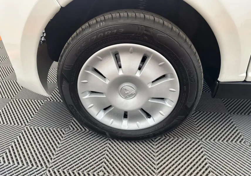 Gros plan sur la roue avant droite blanche d'une Aixam Ambition 0.5 City Pack avec jante argentée et logo central.