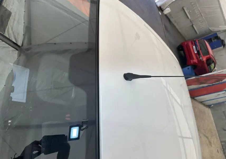 Vue plongeante sur le toit blanc d'une Aixam Ambition 0.5 City Pack avec antenne centrale, en intérieur d'atelier.