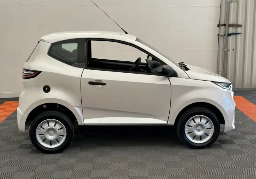 Vue de profil côté gauche d'une AIXAM AMBITION 0.5 CITY PACK blanche avec rétroviseur caméra côté conducteur.