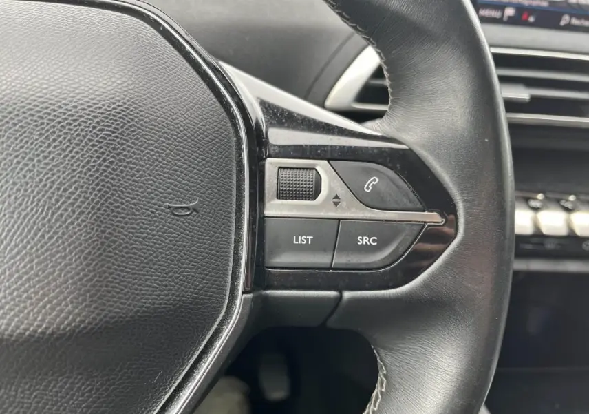 Gros plan sur les commandes au volant droit en cuir noir du Peugeot 3008 2017, avec boutons multifonctions et tableau de bord en arrière-plan.