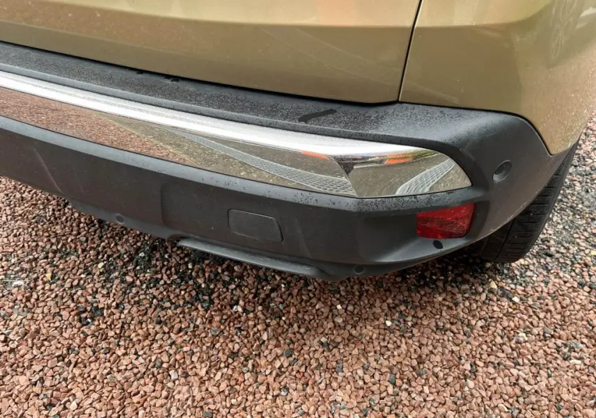 Gros plan sur le pare-chocs arrière droit jaune clair du Peugeot 3008 avec feu antibrouillard et capteurs de stationnement.