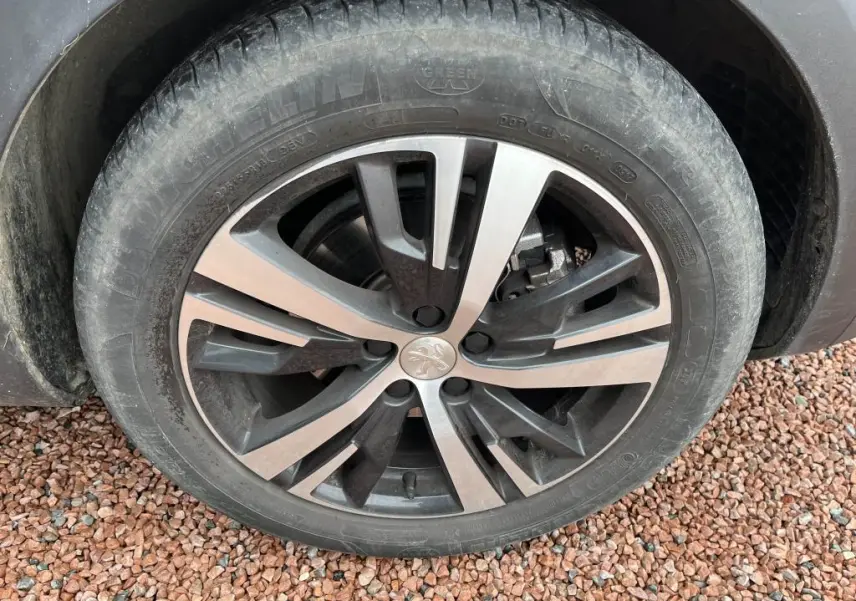 Gros plan sur la roue avant droite du Peugeot 3008 2017, jante alliage bicolore avec logo Peugeot au centre.