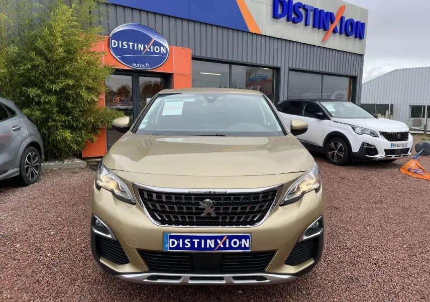 Vue de face du Peugeot 3008 jaune clair métallisé, avec calandre noire et logo lion au centre, devant un concessionnaire.