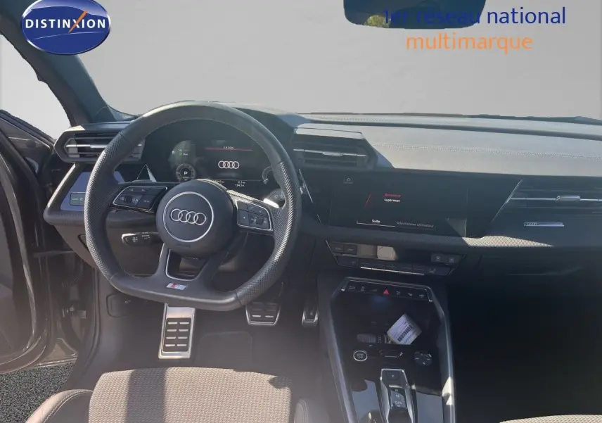 Vue intérieure de l'Audi A3 Sportback 2025, tableau de bord et volant multifonction en cuir noir, ambiance moderne et épurée.