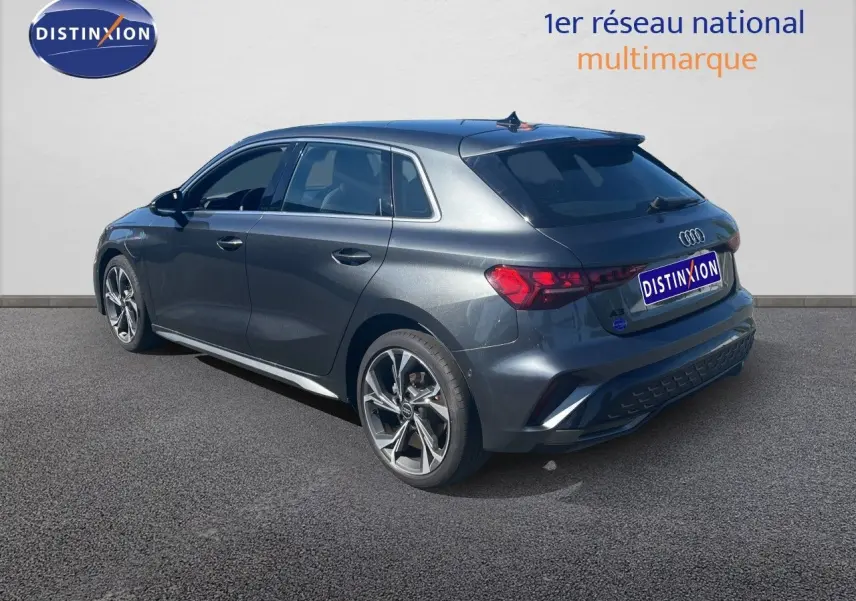 Audi A3 Sportback gris Daytona vue 3/4 arrière droit, finition S-Line avec jantes alliage et feux LED distinctifs.