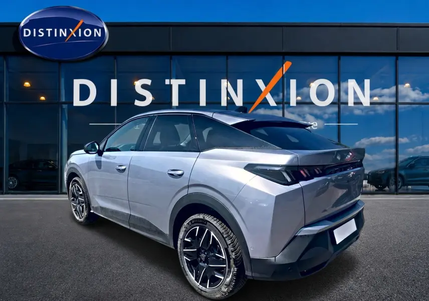 Vue 3/4 arrière droite d’un Peugeot 3008 gris 2025 avec jantes alu noires devant une vitrine Distinxion.