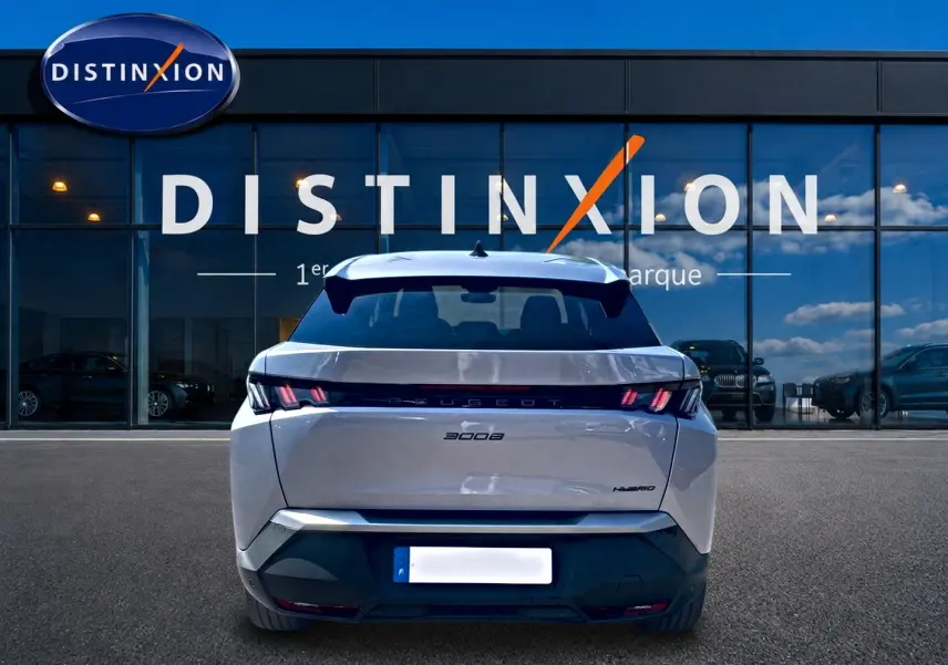 Vue arrière d'un Peugeot 3008 gris 2025 hybride, avec feux arrière LED et becquet arrière visible devant une vitrine Distinxion.