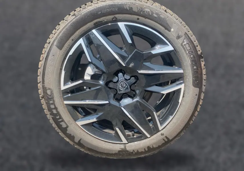 Gros plan sur une jante alu noire et grise avec logo Peugeot au centre, montée sur un pneu Michelin.