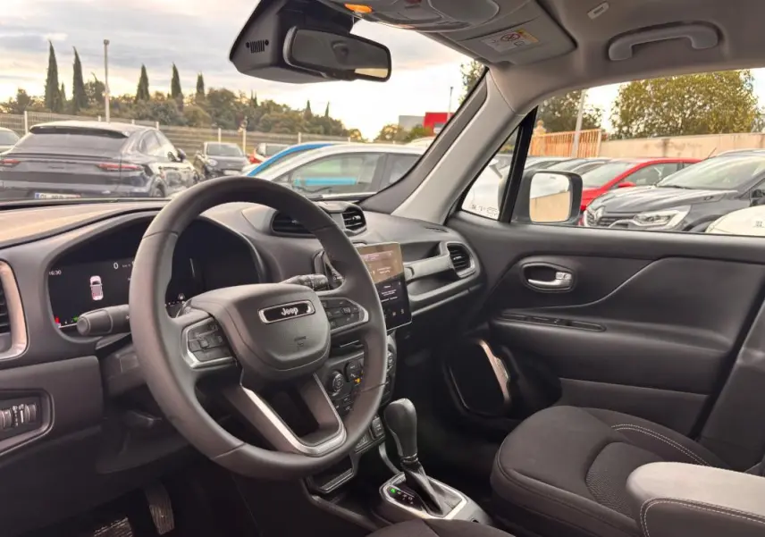 Vue intérieure côté conducteur du Jeep Renegade blanc 2024, avec volant multifonction et écran tactile central visible.