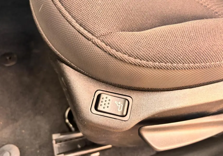 Bouton de réglage de siège chauffant sur le côté gauche d’un siège en tissu beige dans un Jeep Renegade 2024.