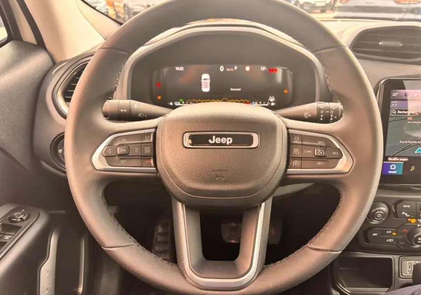Vue rapprochée du volant noir du Jeep Renegade 2024 avec tableau de bord numérique et commandes intégrées.