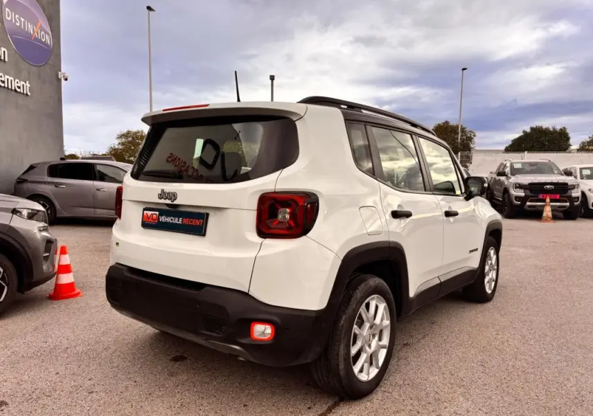 Vue 3/4 arrière droite d'un Jeep Renegade blanc 2024 avec feux arrière carrés et protections noires sur pare-chocs.