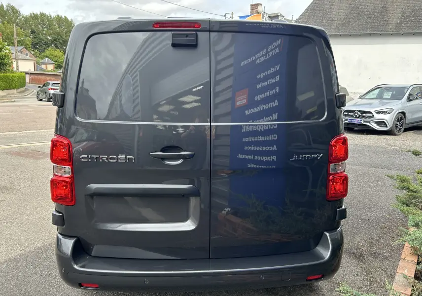 Vue arrière d'un Citroën Jumpy gris titane 2025 avec portes battantes et feux arrière rouges visibles.
