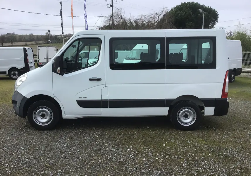 Vue de profil côté gauche d’un Renault Master Combi III blanc, fourgon 9 places avec fenêtres latérales et jantes acier.