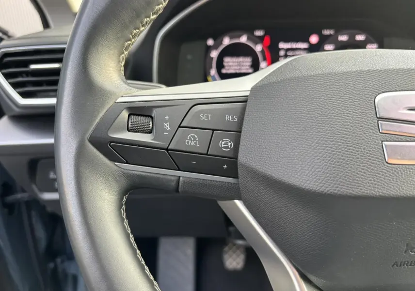 Gros plan sur le volant cuir multifonction du SEAT Leon 2.0 TDI 115 Style avec commandes de régulateur de vitesse.