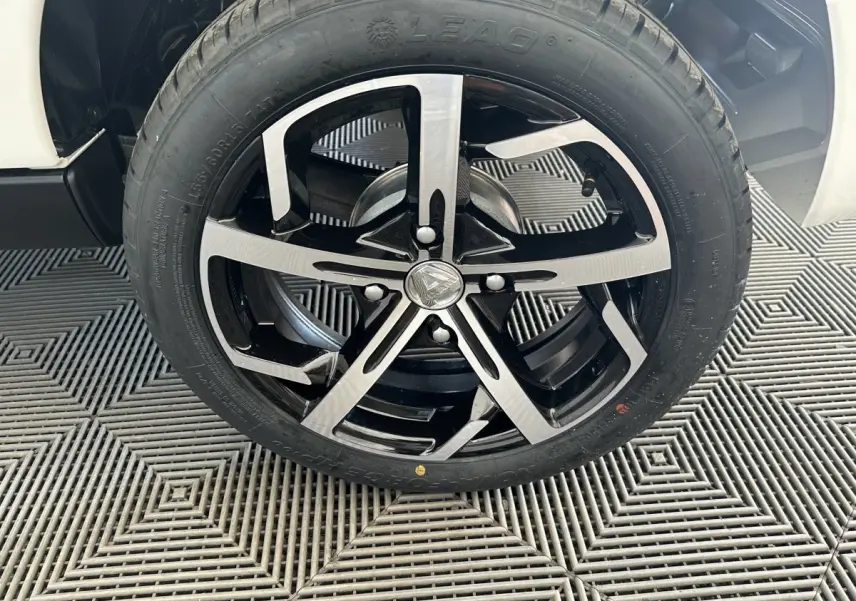 Gros plan sur la roue avant droite de l'AIXAM AMBITION 0.5 CROSSOVER PREMIUM blanche avec jante noire et argentée.